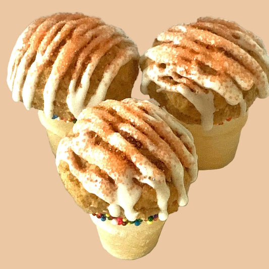 Three ice cream cone-shaped pastries with a drizzled topping on a light background